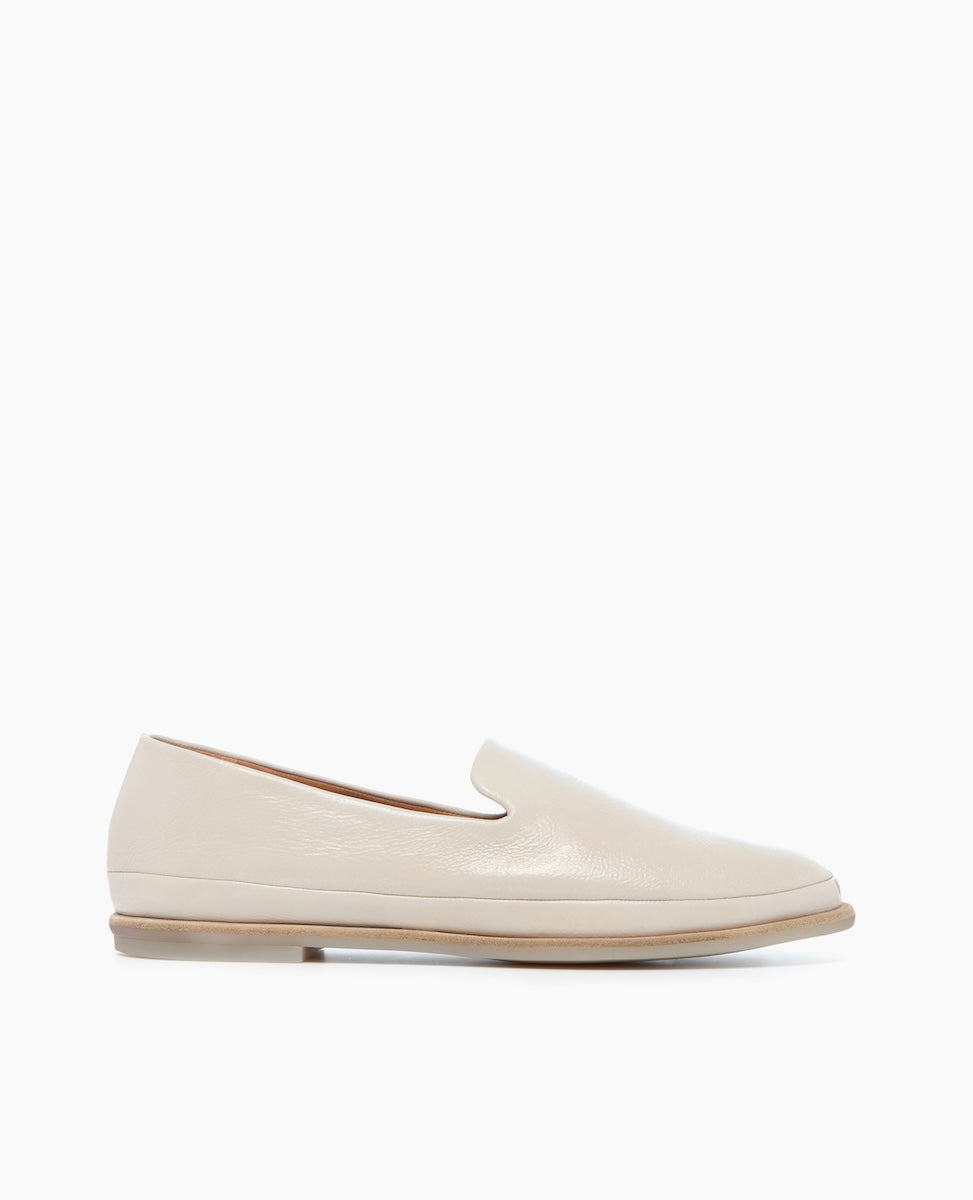 A sleek, cream-colored leather loafer with a smooth texture, featuring a low-profile design, rounded toe, and a thin, light brown sole.