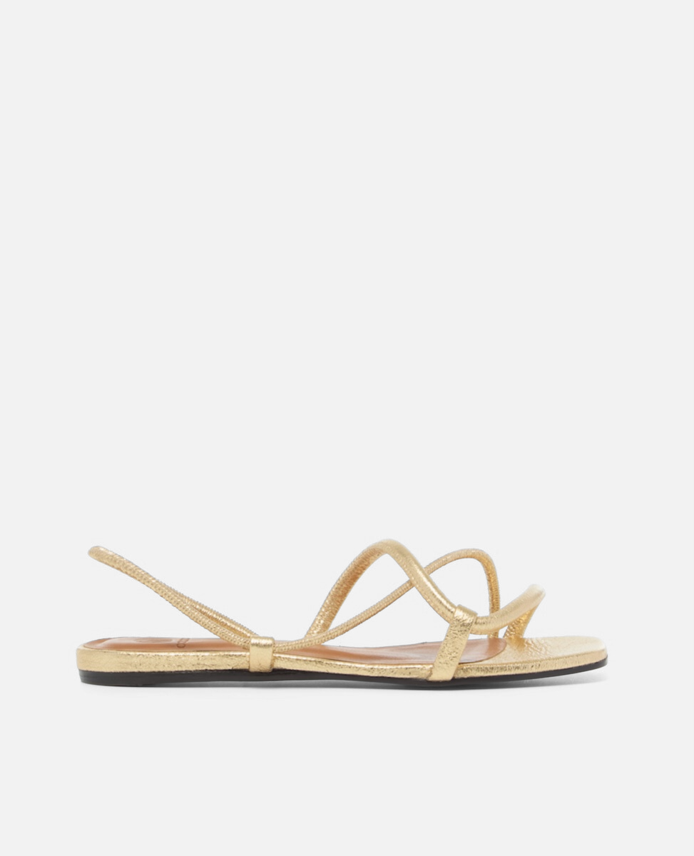 Side view of a crinkled metallic gold flat sandal with slim cylindrical padded straps and an elasticated slingback, square toe, on a white background.