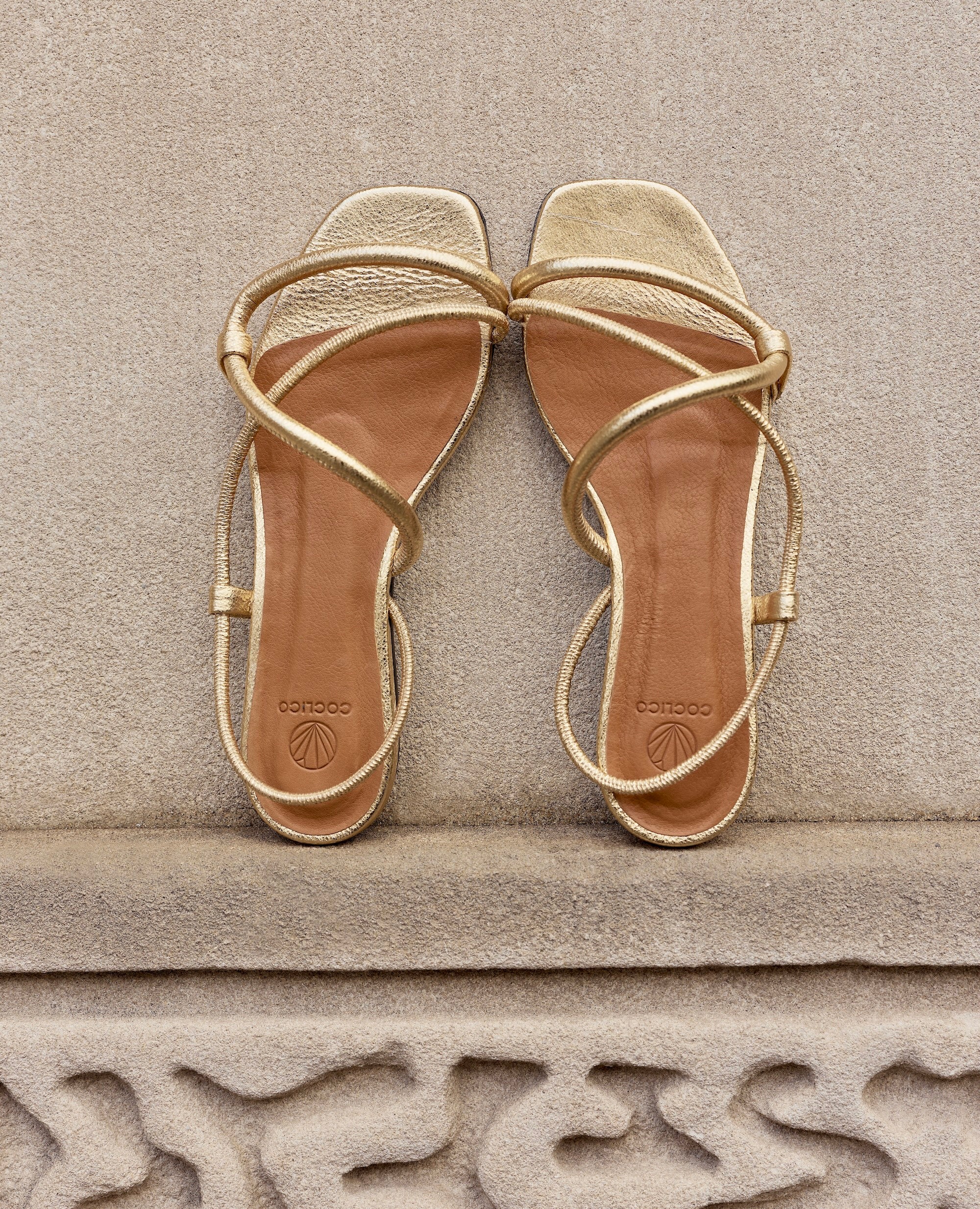 Pair of gold sandals on a stone surface