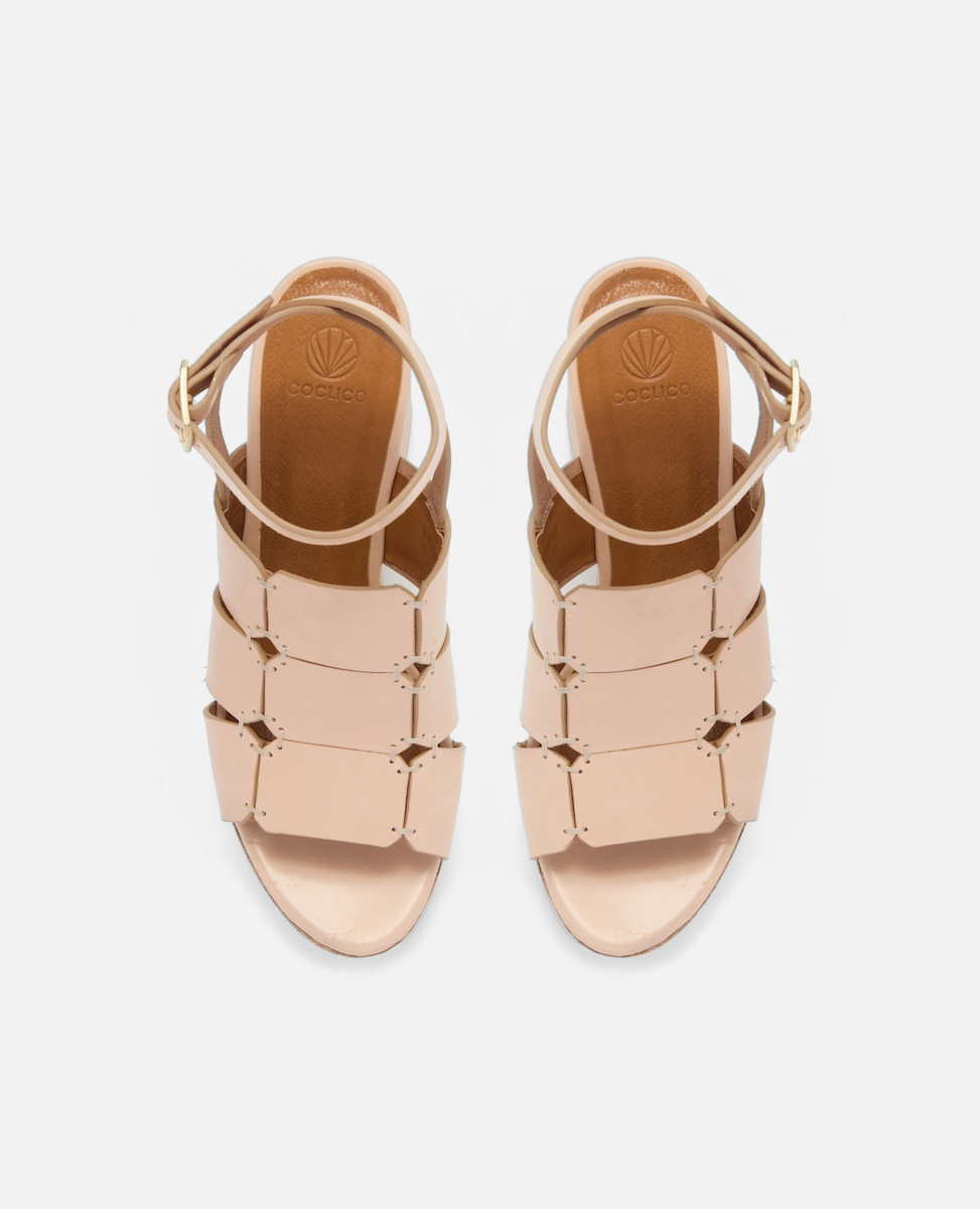 Top view of a natural vachetta leather platform sandal with octagonal cage straps, hand-stitched detailing, slim ankle strap with buckle, and a solid cork heel and platform, on a white background.