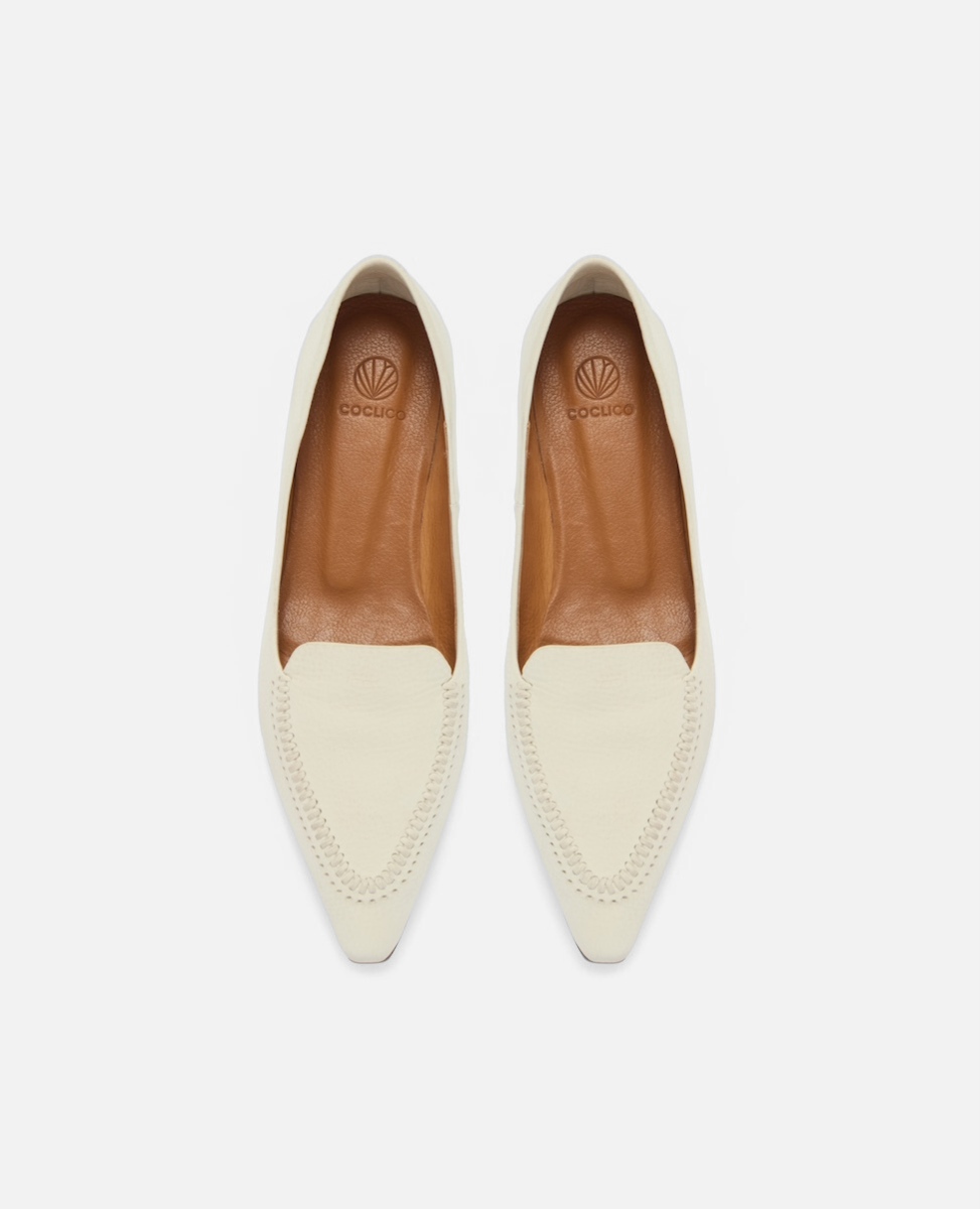 Top view of a pointed-toe white nubuck leather loafer with topstitch detailing and a flat leather sole on a white background
