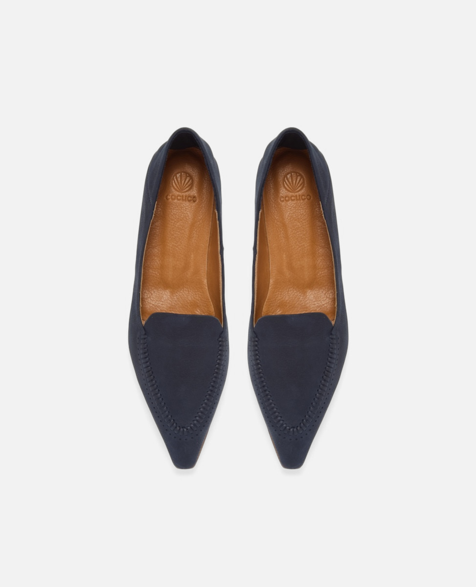 Top view of a pointed-toe navy nubuck leather loafer with topstitch detailing and a flat leather sole on a white background
