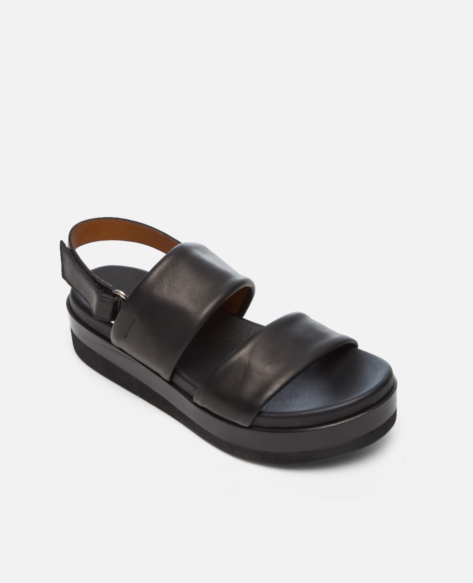 A black leather sandal with a thick platform sole, featuring two wide straps across the foot and an adjustable ankle strap with a buckle.