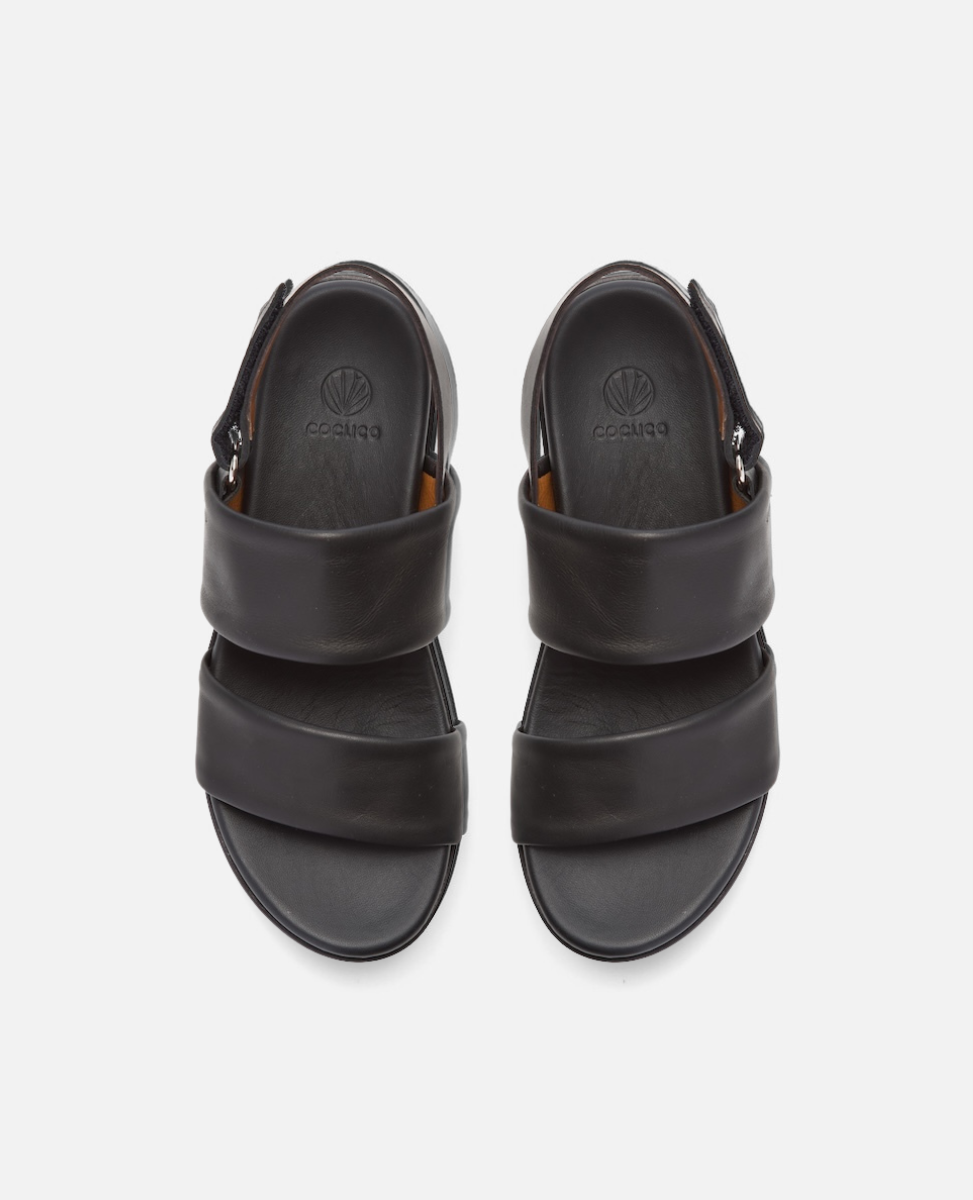A pair of black leather sandals with two wide straps across the top, a closed heel, and a round toe, featuring a subtle embossed logo on the insole.