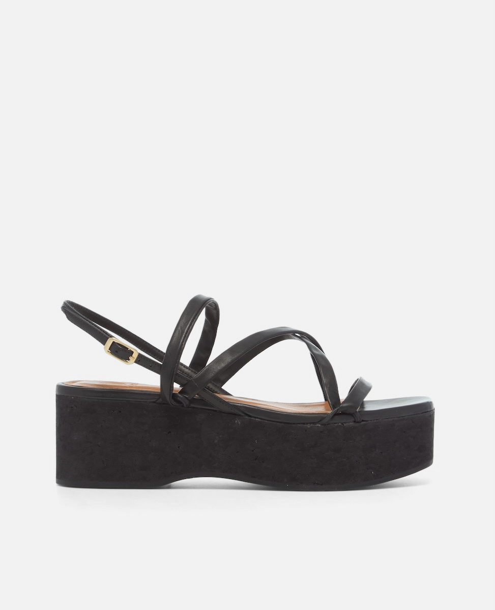 Side view of a black leather cork wedge sandal with slim crisscross straps, adjustable slingback, and a sculptural cork platform sole