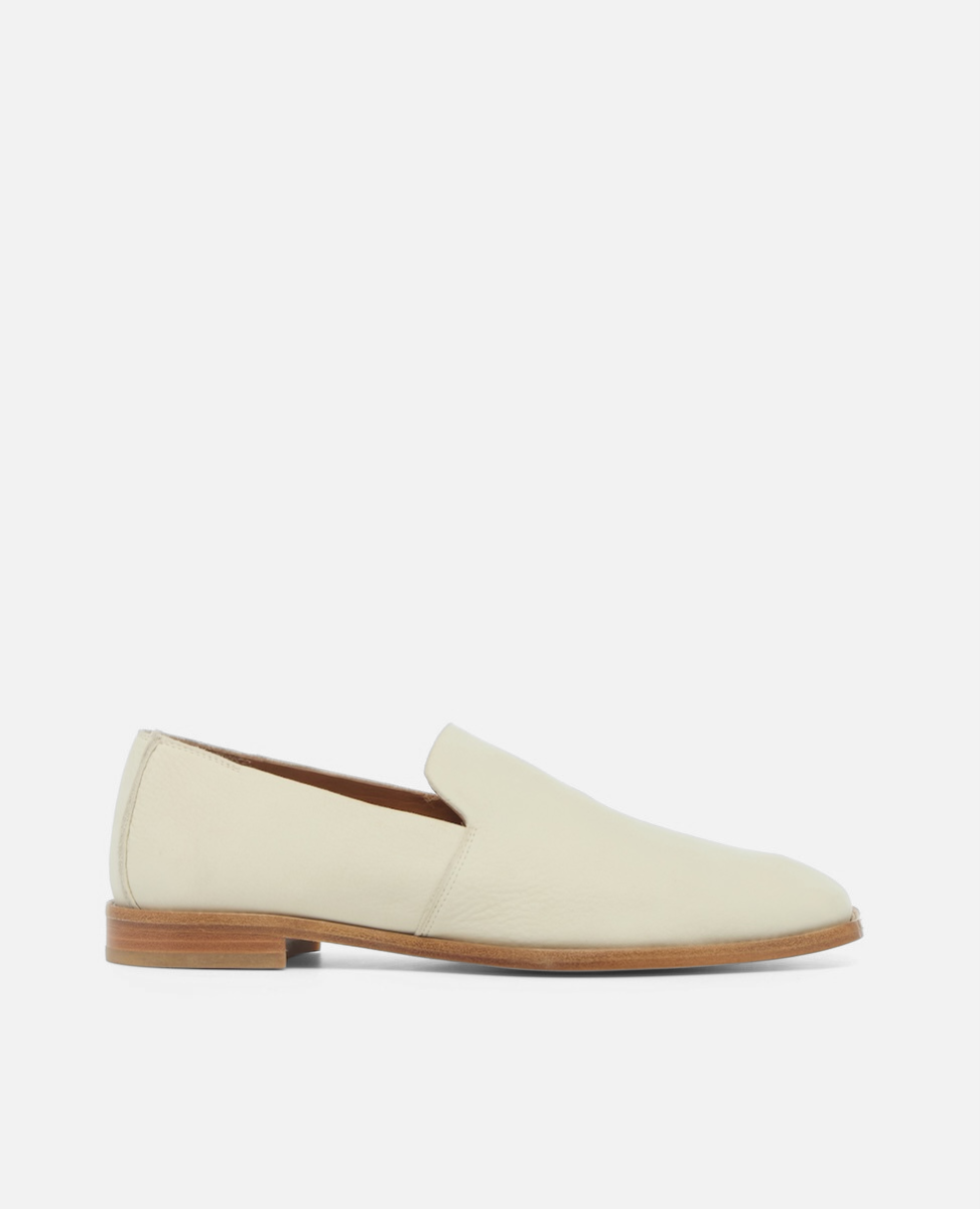 Side view of a white nubuck leather slip-on loafer with a tapered square toe and low stacked heel on a white background