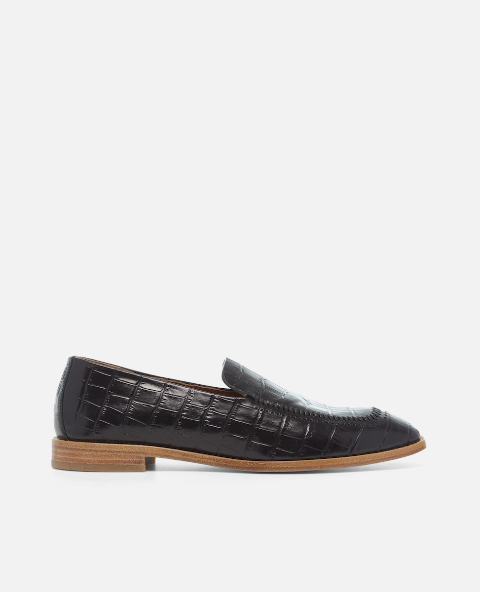 Side view of a black croc-embossed leather loafer with a softly squared toe and low stacked heel on a white background