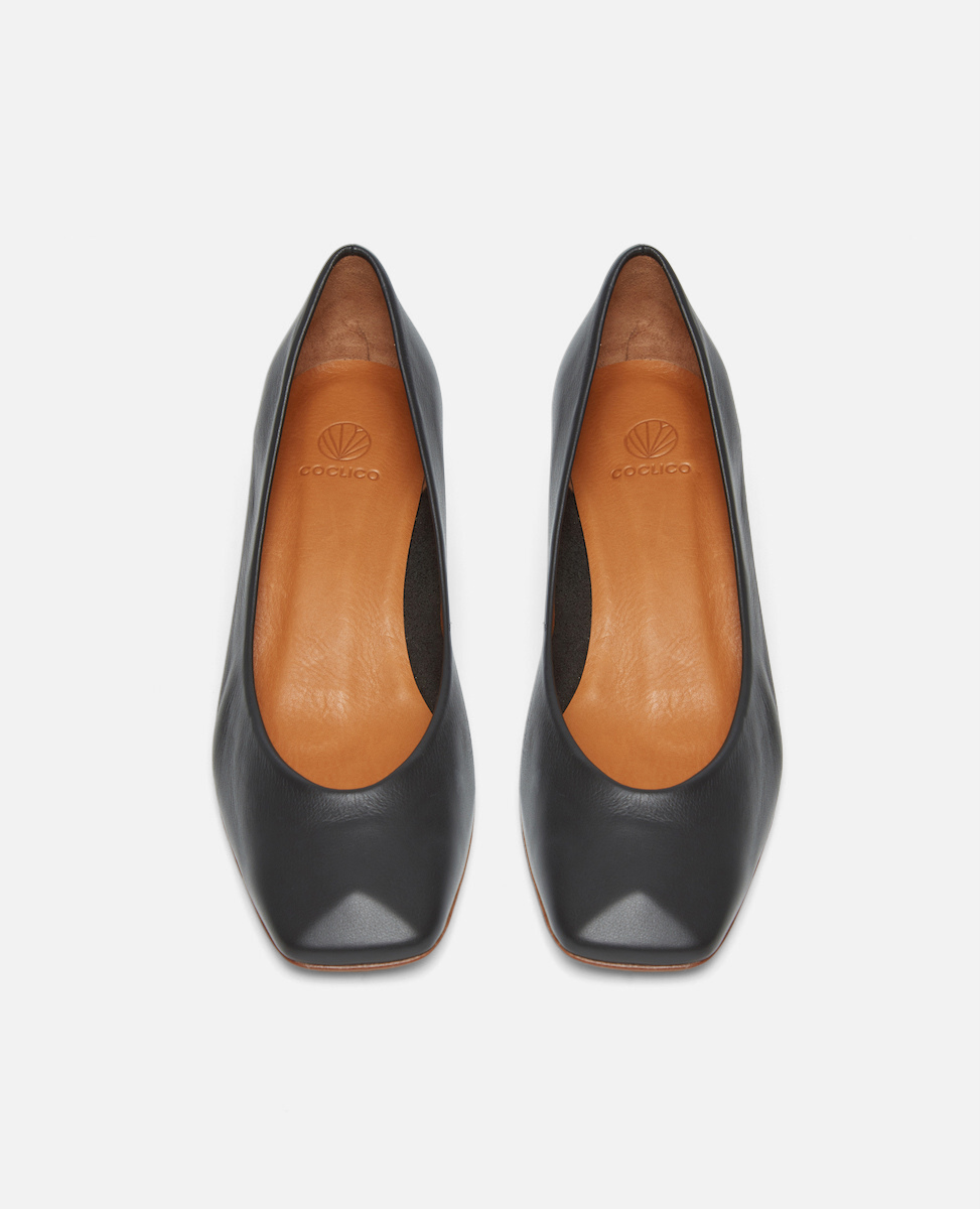 Pair of black mid-heeled shoes with a sculpted square toe with tan insoles on a white background
