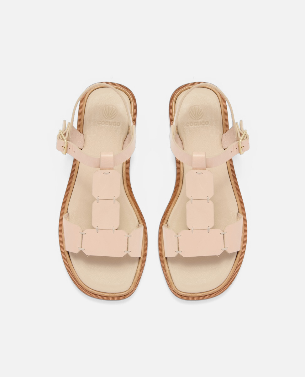 Top view of a natural leather T-strap sandal with hand-linked panels, slim ankle strap, and a sleek flexible leather sole with a textured welt.
