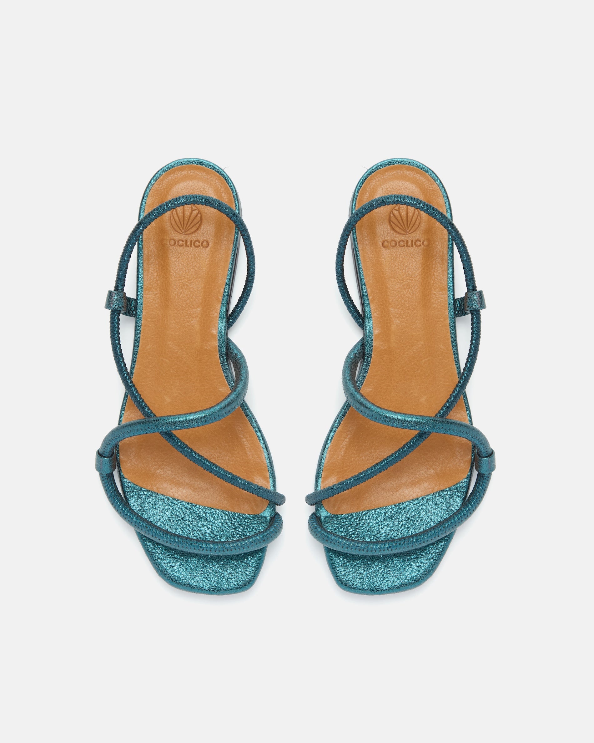 Top view of a metallic blue crinkled leather flat sandal with slim padded straps, elasticated slingback, and a square toe on a grey background