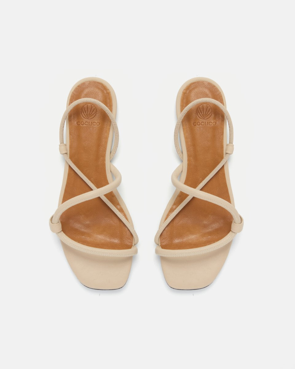 Pair of beige sandals with criss-cross straps on a white background