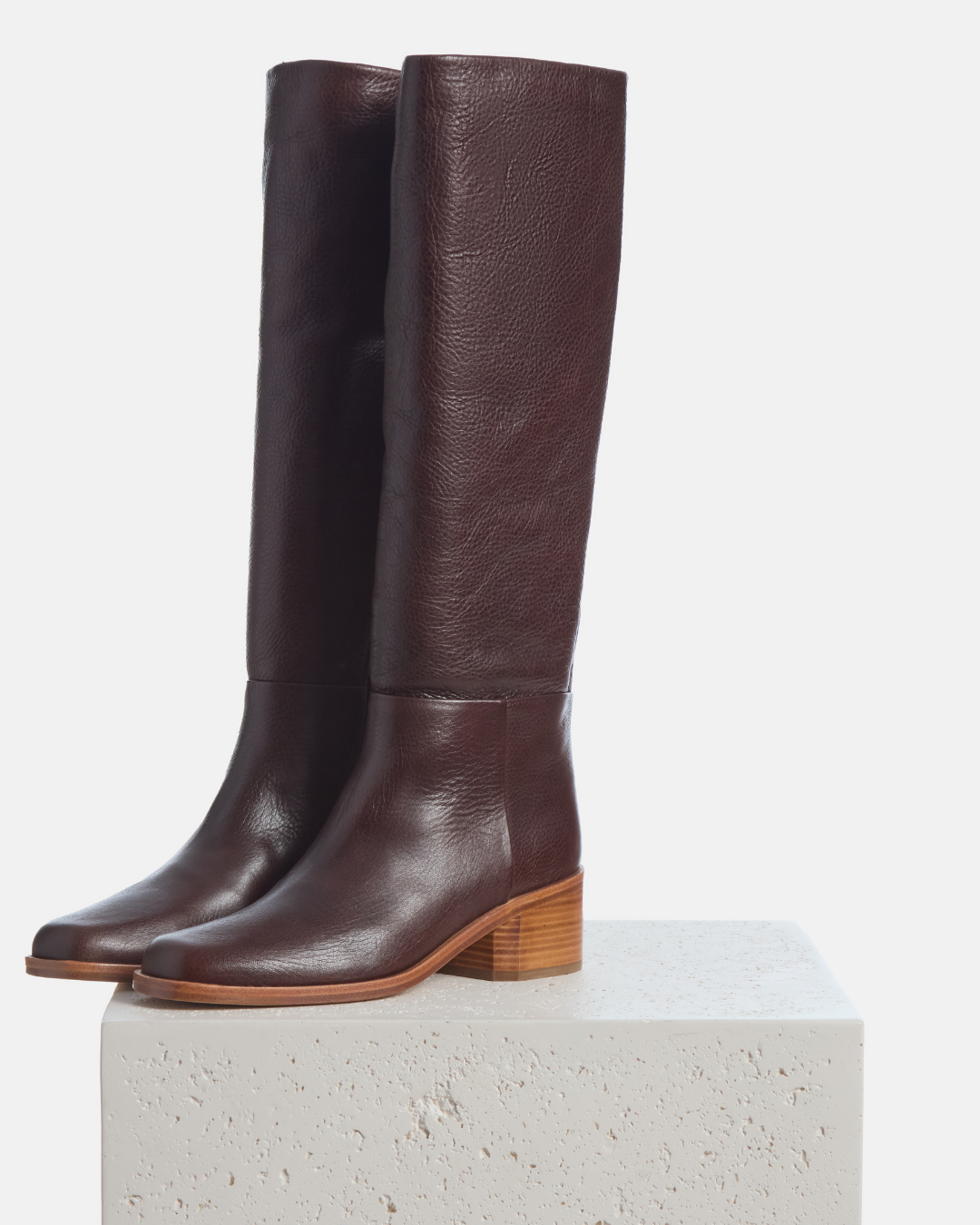 Coclico Alto Boot in Castagno, chestnut brown leather knee high boots styled on a stone plinth