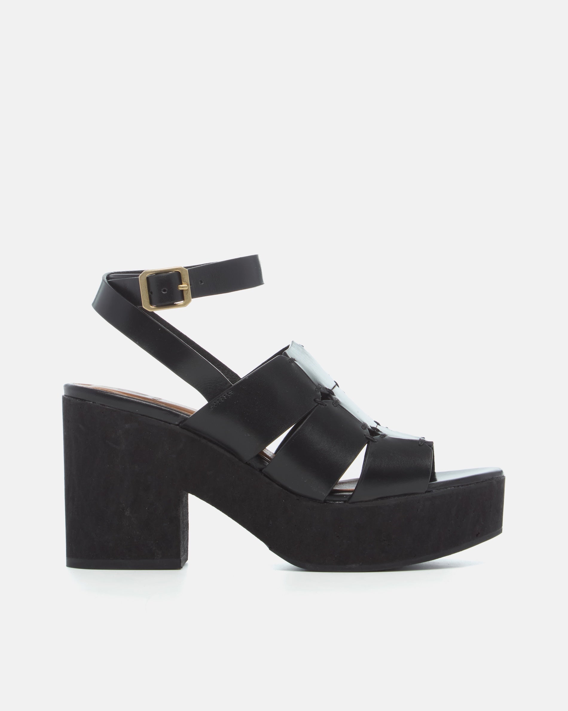 Side view of a black vachetta leather platform sandal with octagonal cage straps, hand-stitched detailing, slim ankle strap with buckle, and a solid cork heel and platform, on a white background.