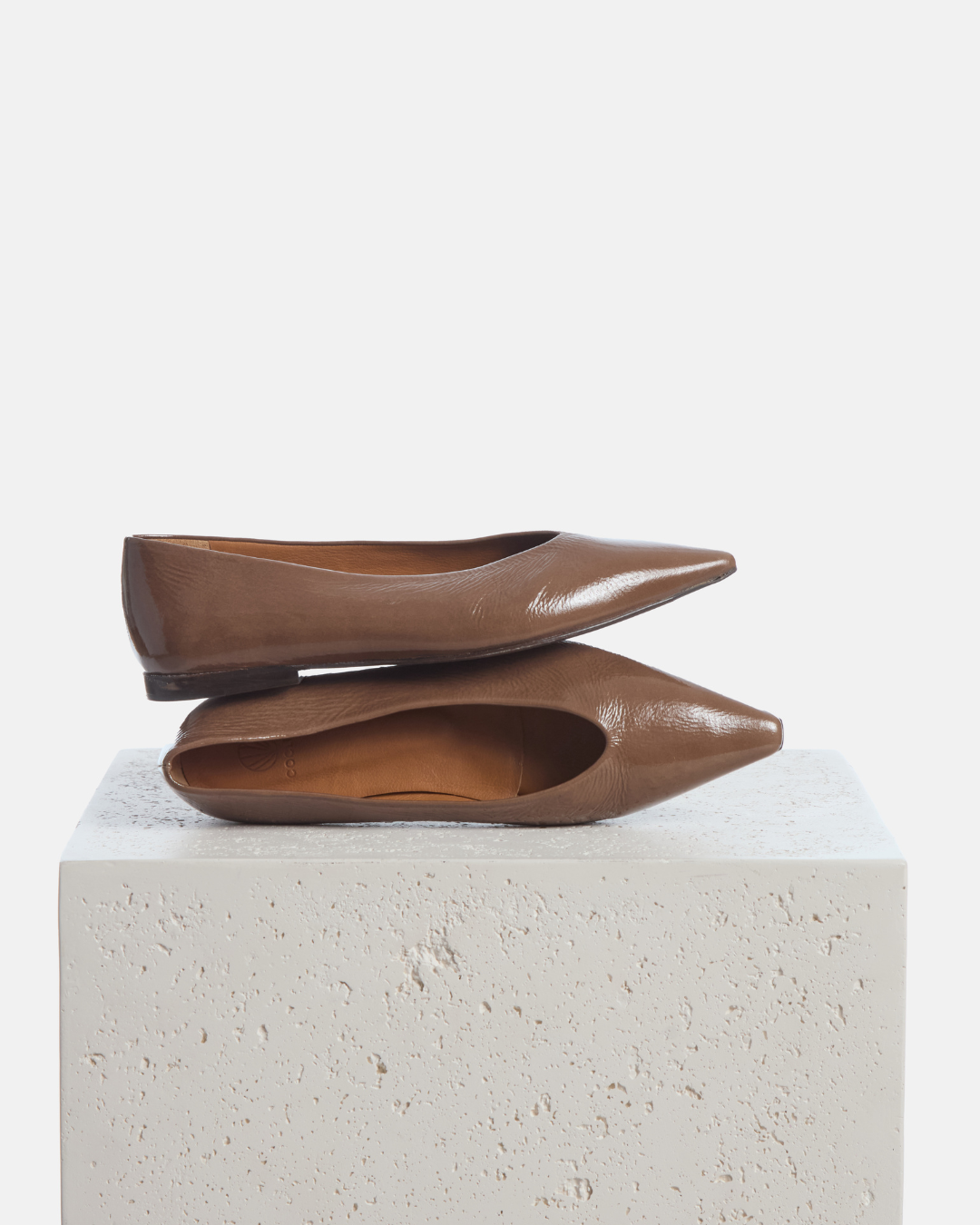 Coclico Cabnal Ballet Flat in Boue crinkled patent, brown pointed toe flats styled on a stone plinth
