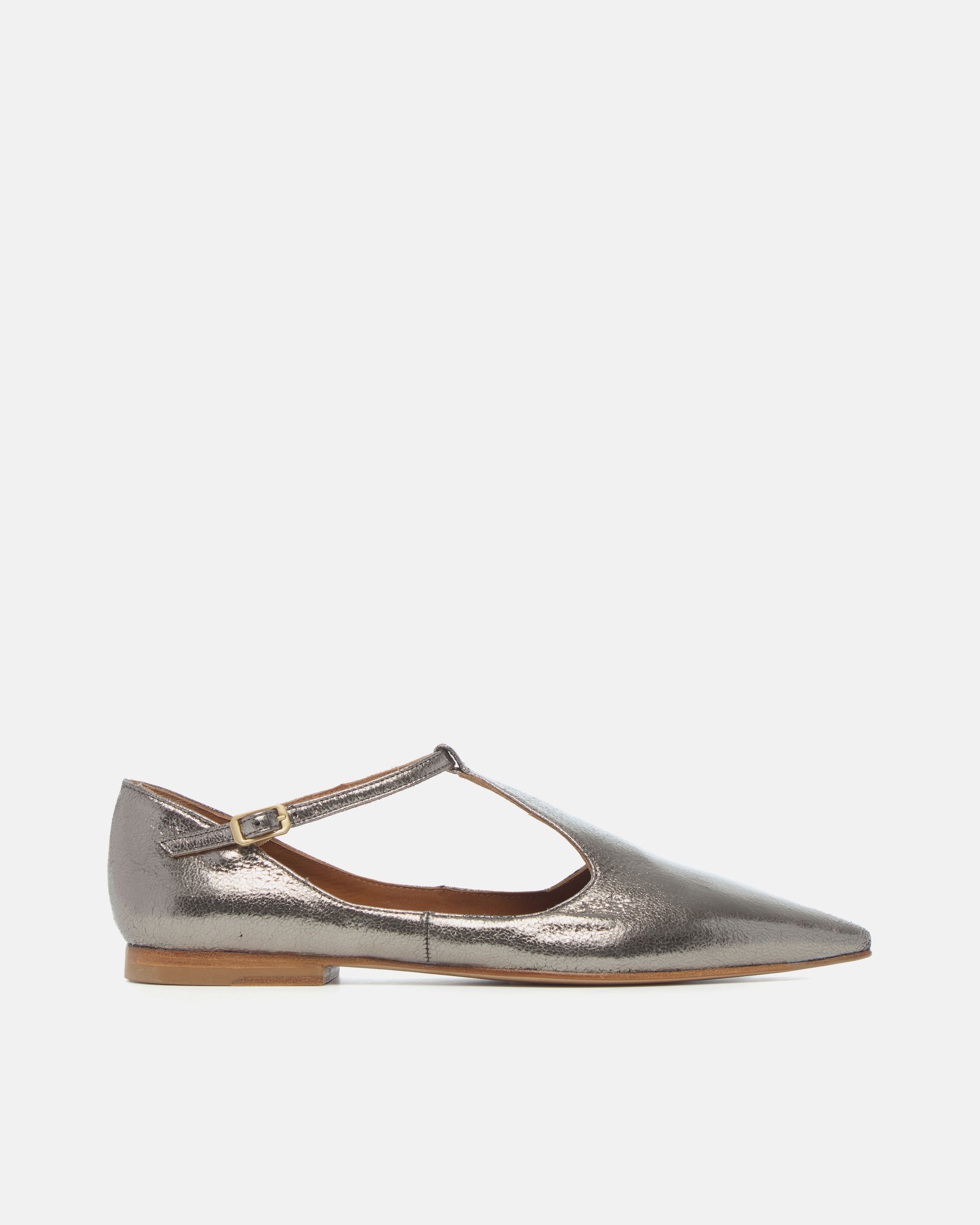 Side view of a pointed-toe silvery metallic T-strap flat with adjustable buckle and leather sole on a white background