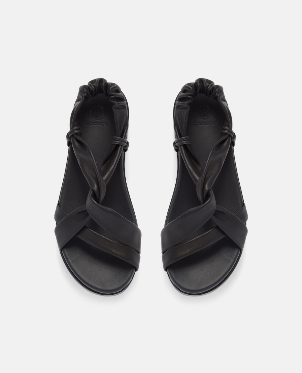Top view of a black Coclico tubular leather sandal with a platform sole on a grey background