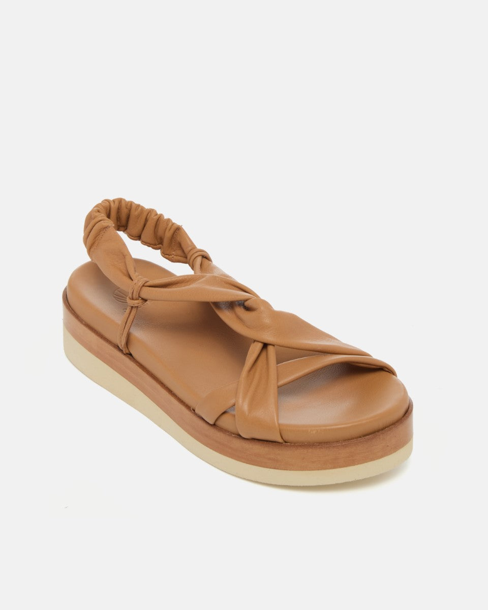 Angled view of pale brown leather wedge sandal with softly twisted straps, elasticized back strap, and a lightweight EVA platform sole on a white background.