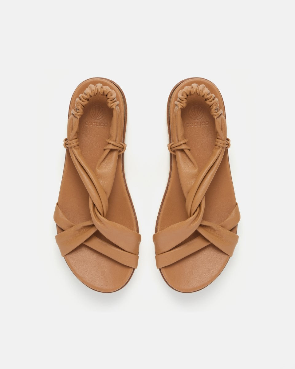 Front view of pale brown leather wedge sandal with softly twisted straps, elasticized back strap, and a lightweight EVA platform sole on a white background.