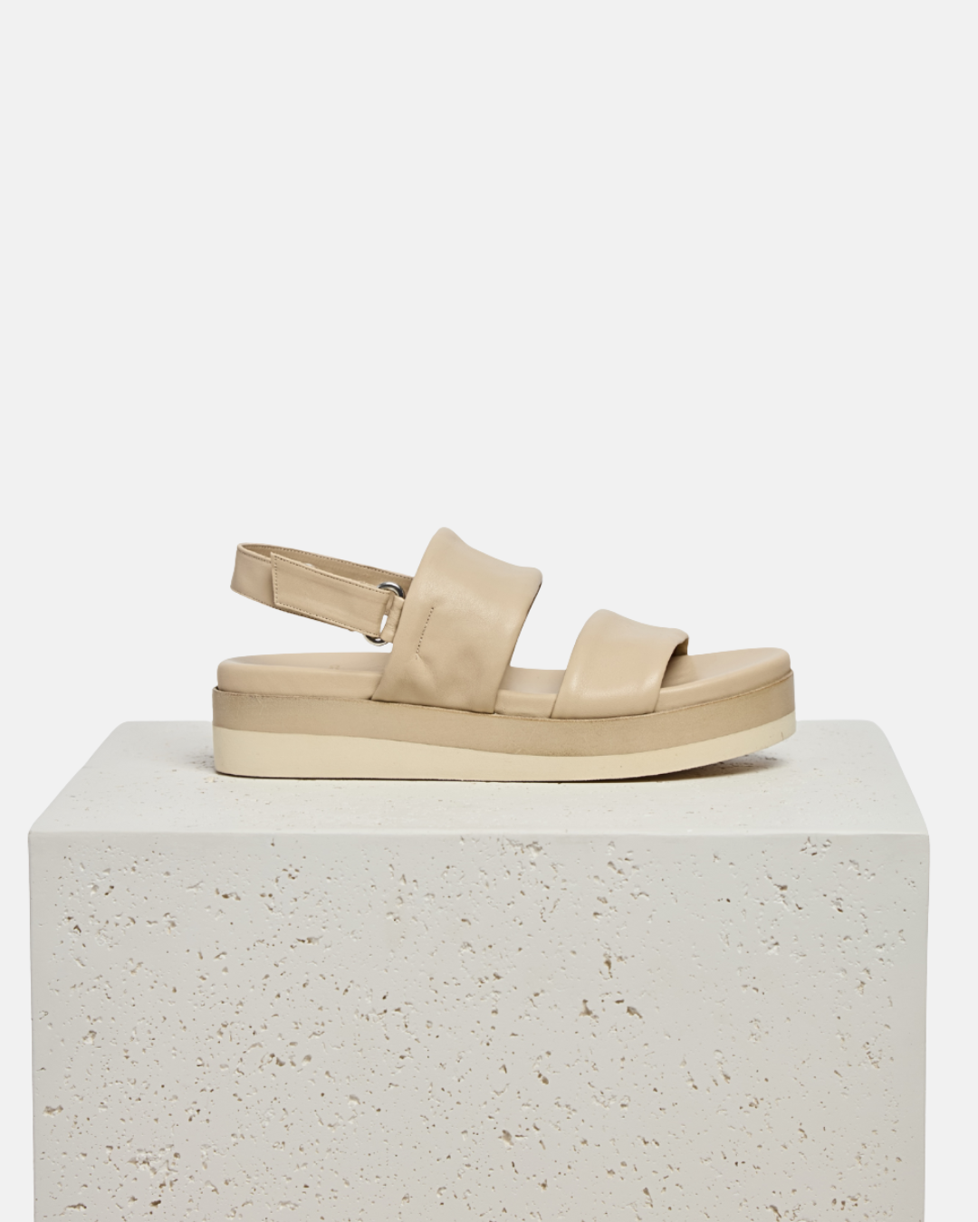 Shoe on a plinth: off-white leather wedge sandal with wide tubular straps, velcro slingback, and a lightweight EVA platform sole