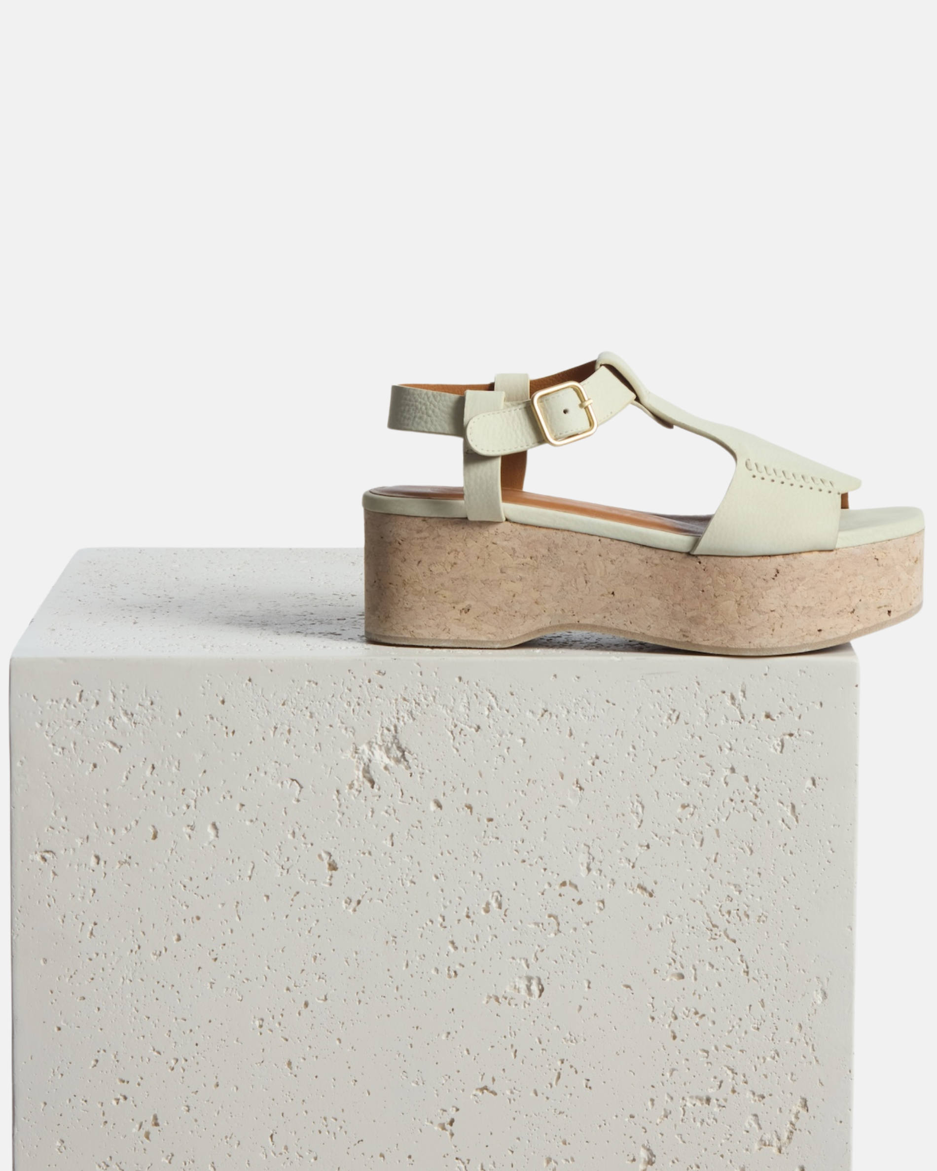 wege on a plinth: white nubuck leather wedge sandal with wide stitched straps, adjustable ankle buckle, and a whitewashed cork platform sole