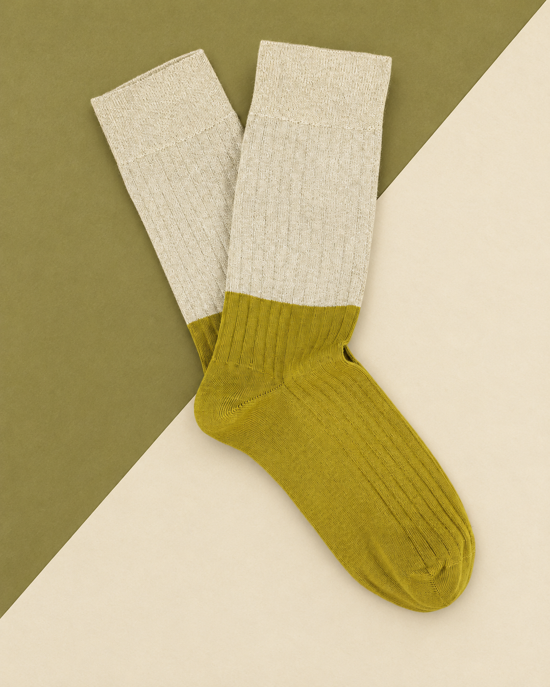 Escuyer Lurex Block socks with a sparkling pale Lurex top and chartreuse yellow ribbed foot, laid flat on a two-tone olive and cream background