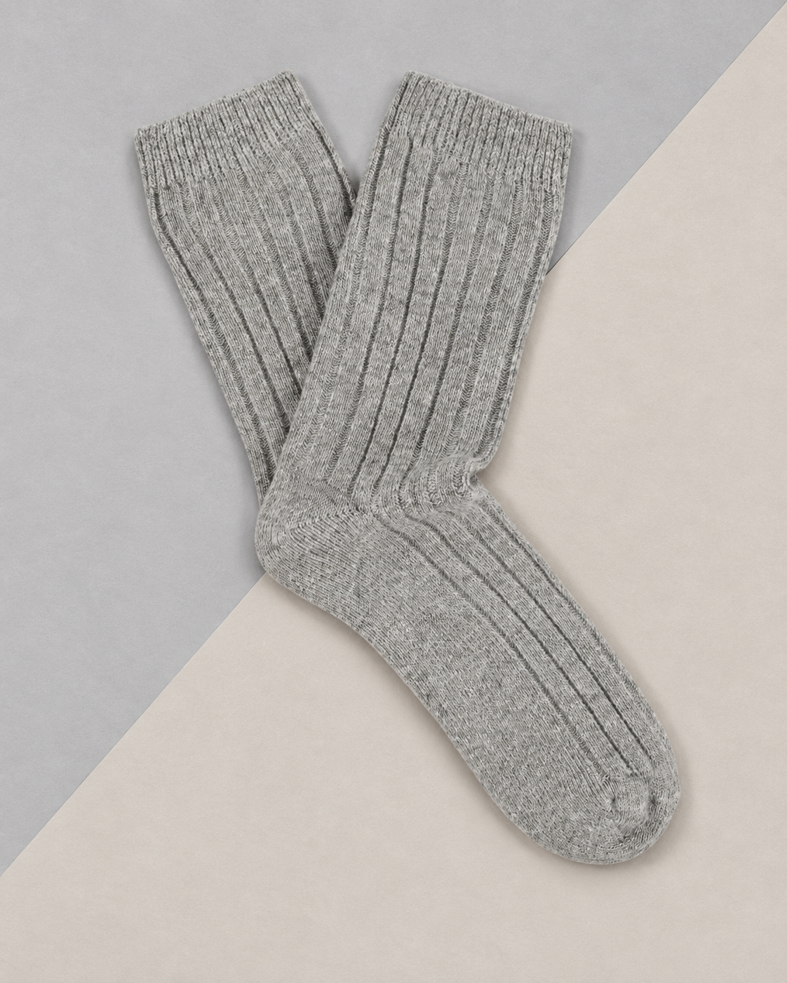 Escuyer cashmere crew socks in Light Grey laid flat on a two-tone grey background
