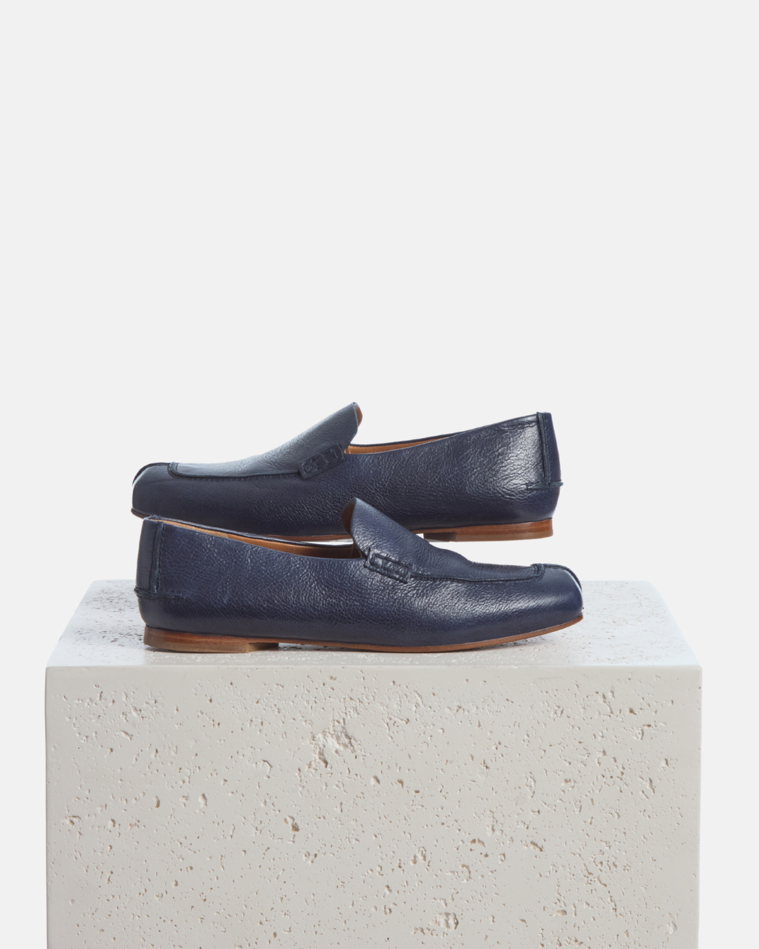 Coclico Francis Loafer in Marino, navy leather loafers styled on a stone plinth