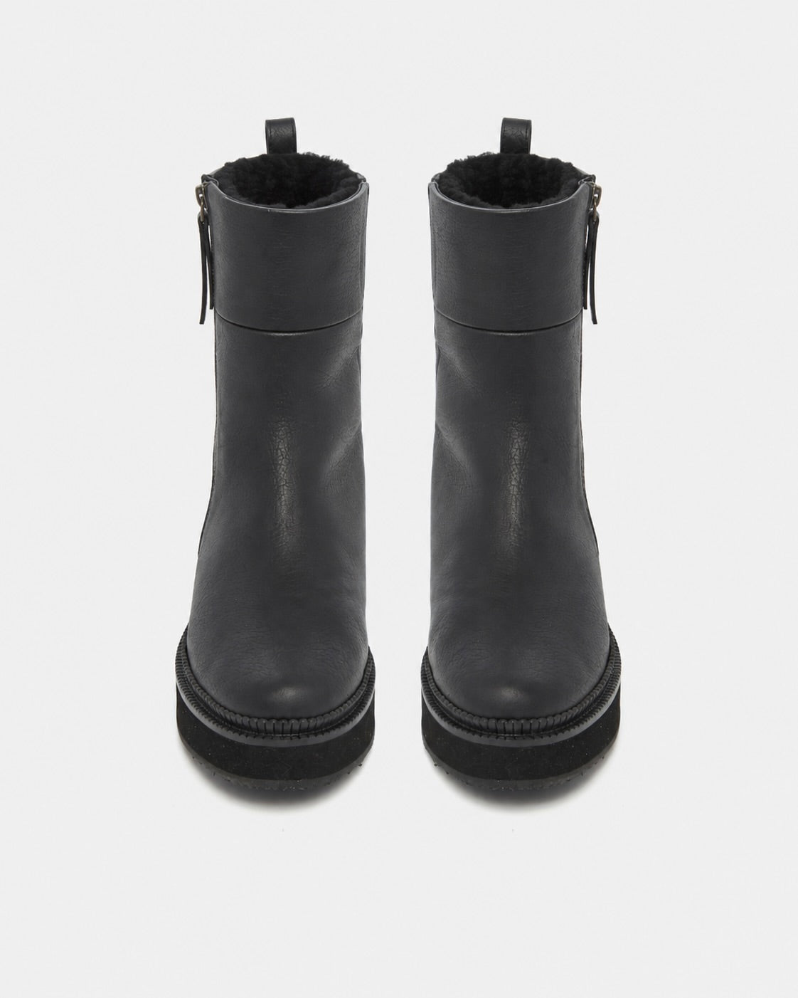 A pair of black leather ankle boots with side zippers and a soft black faux-fur lining, shown from a front-facing overhead perspective on a light gray background.