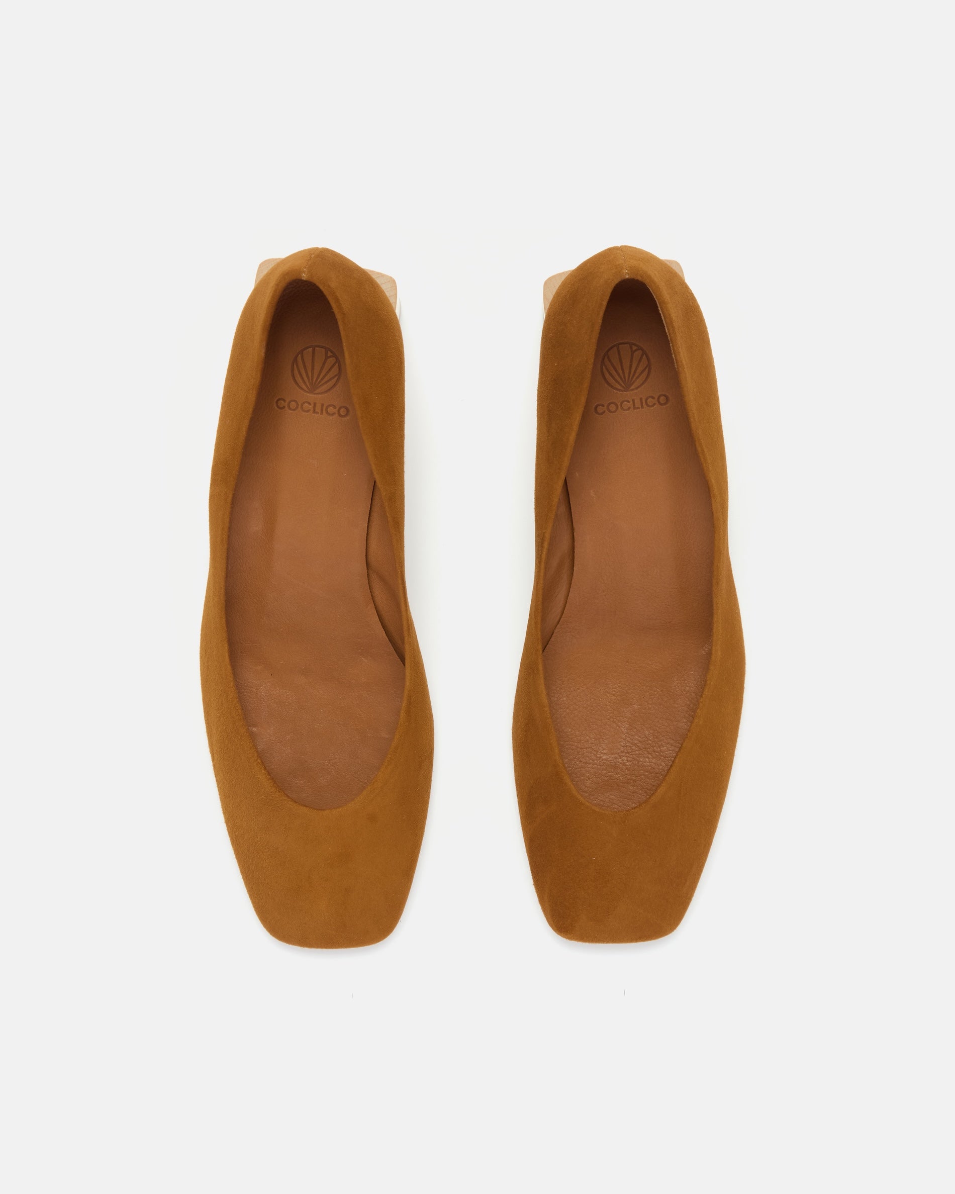 Top view of a brown suede pump with a square toe and a solid architectural wood block heel on a white background