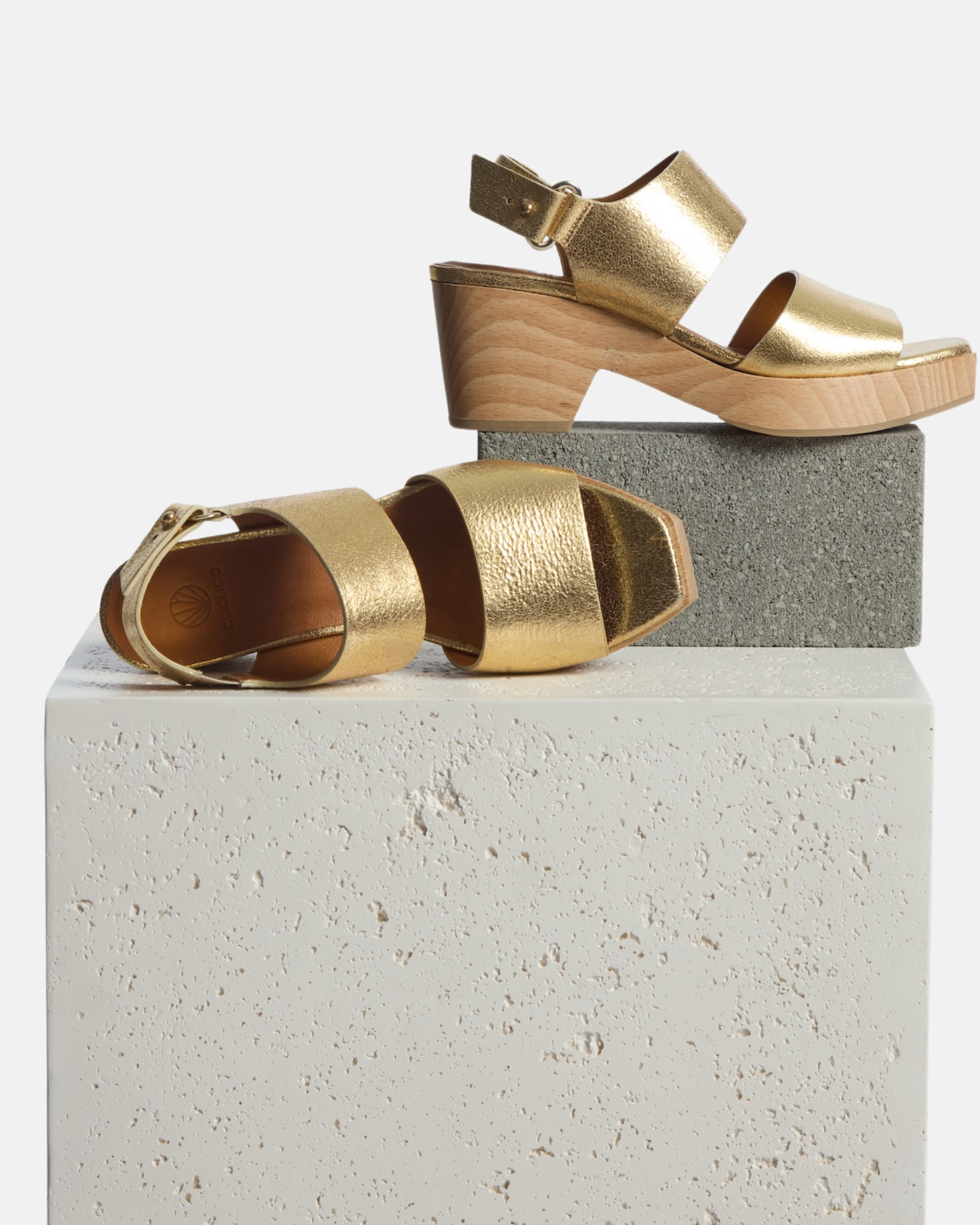 Clogs on plinth: gold leather clog sandal with wide straps, adjustable slingback, squared toe, and solid ash wood block heel