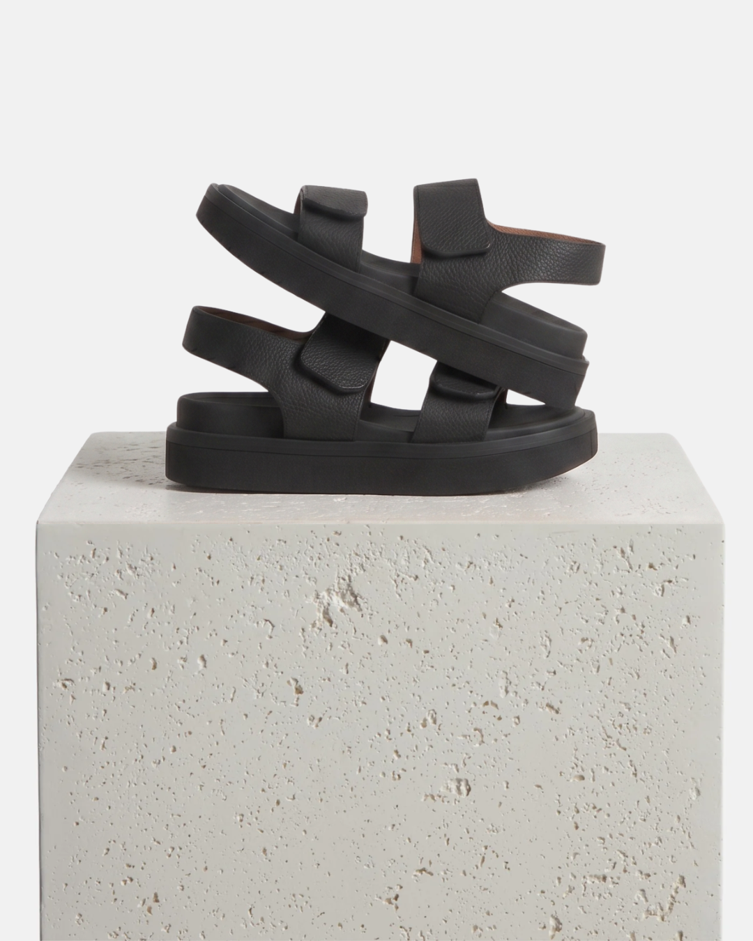 Black wedge footbed sandals with a wide front strap and wide quarter strap fastened by velcro arranged on a plinth