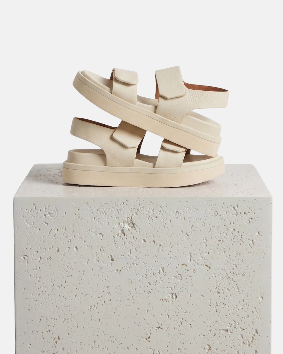 Off white two strap sandal on a plinth