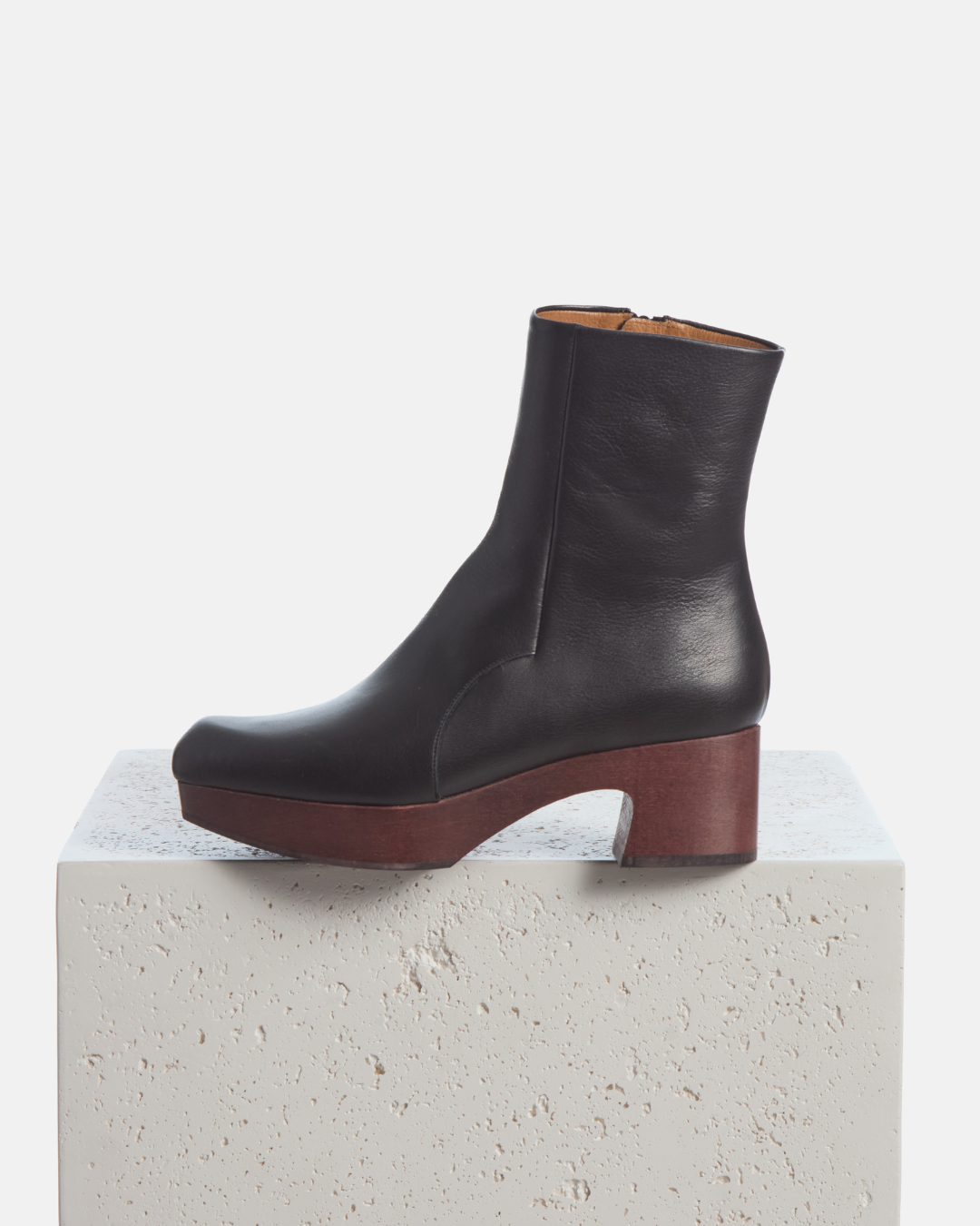 Coclico Quality Clog Boot in black leather, ankle boots on mahogany clog platform heels styled on a stone plinth