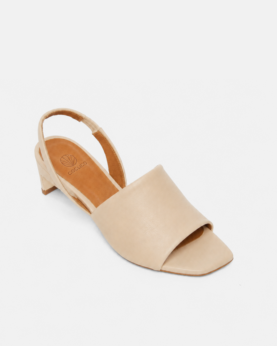 Angled view of a Coclico slingback mid-heel off-white sandal with wide front band.