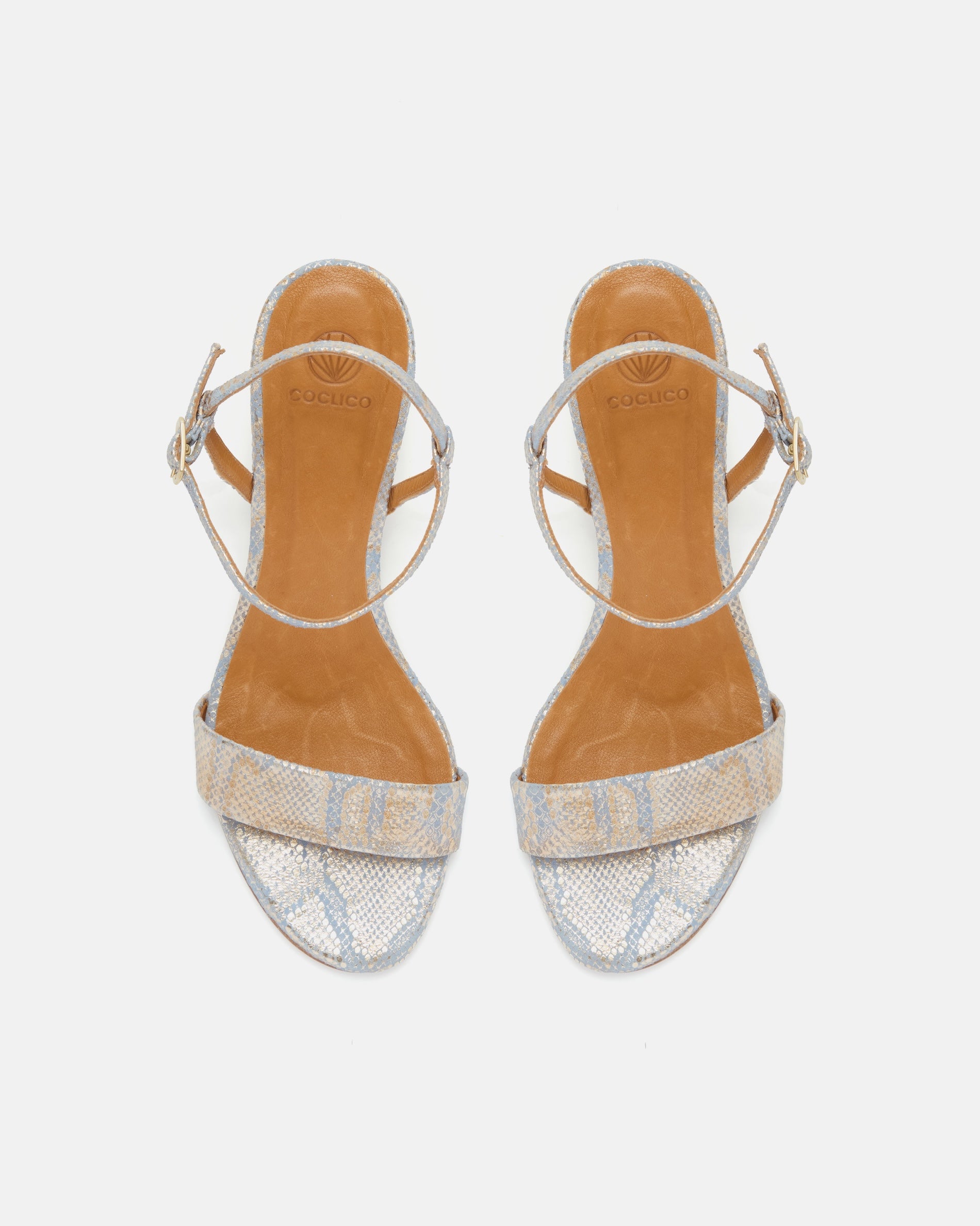 Top view of a gold and blue snake print leather demi-wedge sandal with a slim strap, ankle buckle, and sculptural wooden wedge.