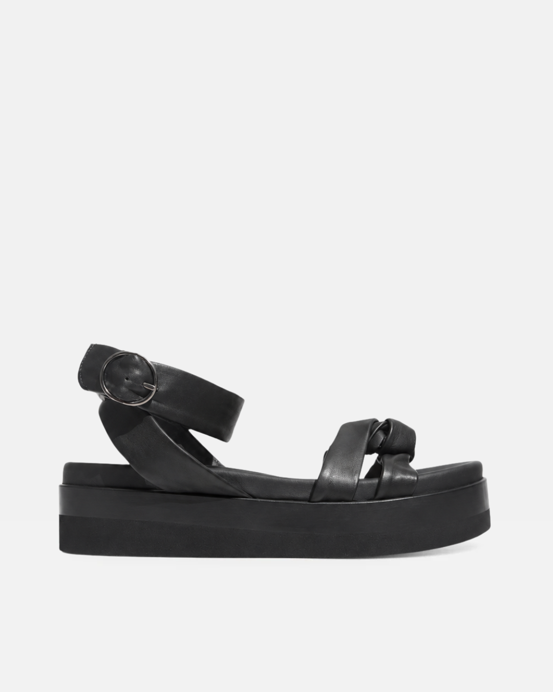 A sleek black sandal with a flat, thick sole, featuring a smooth leather texture, crisscross straps, and a circular buckle on the ankle strap.