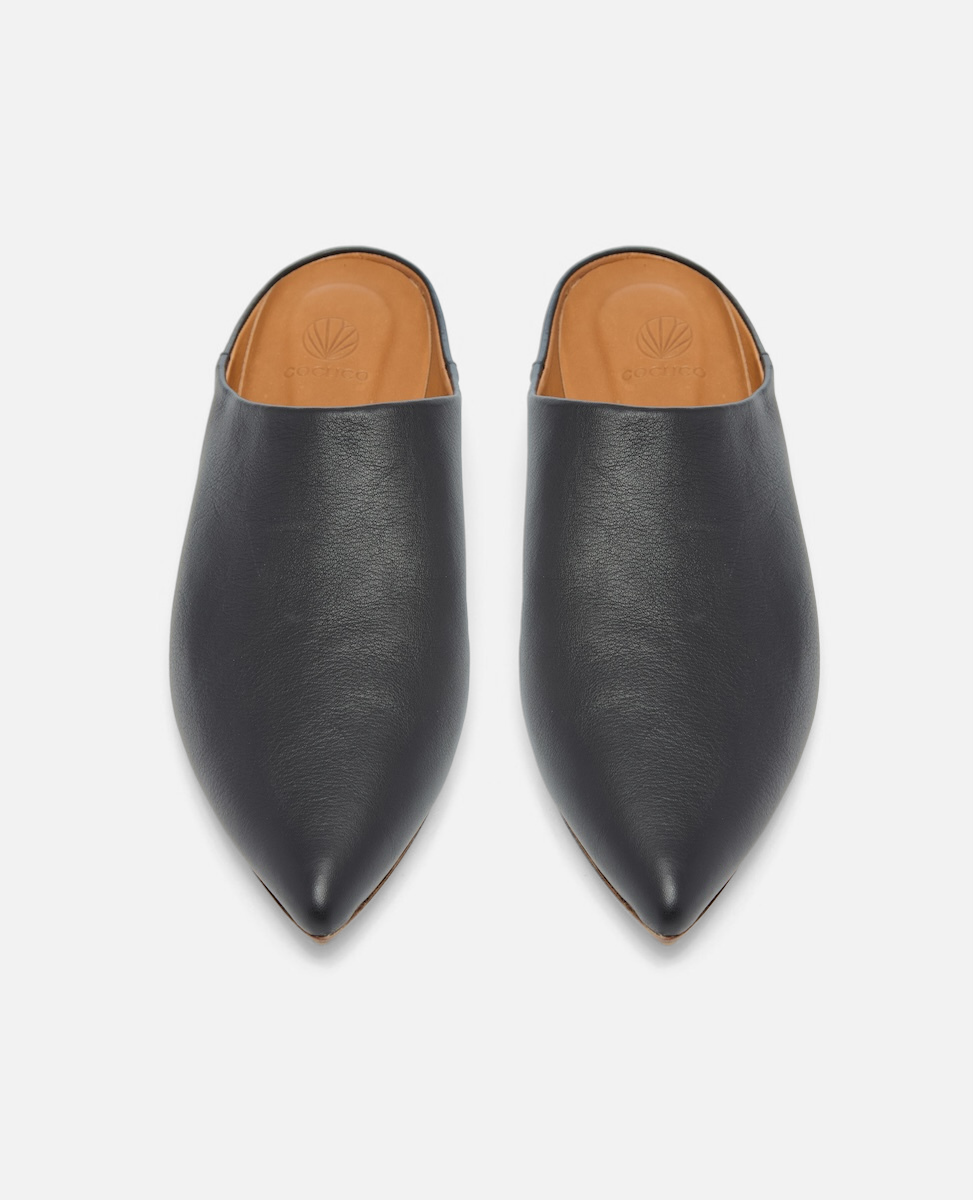 Pair of black leather shoes with tan interior on a light gray background