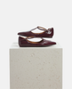 Pair of maroon shoes on a light gray pedestal against a white background 4