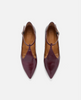 Pair of maroon pointed-toe shoes with brown soles on a white background 1