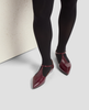 Red shoes with black accents worn with black tights on a light background 5