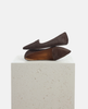 Pair of brown textured loafers on a light gray pedestal against a white background 4