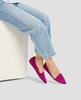 Person wearing magenta pointed-toe flats and light blue jeans on a white background 5