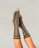 Patterned socks in brown and black worn by a person on a light gray background 1