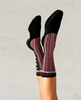 Black shoes and striped socks worn by a person on a light gray background 1