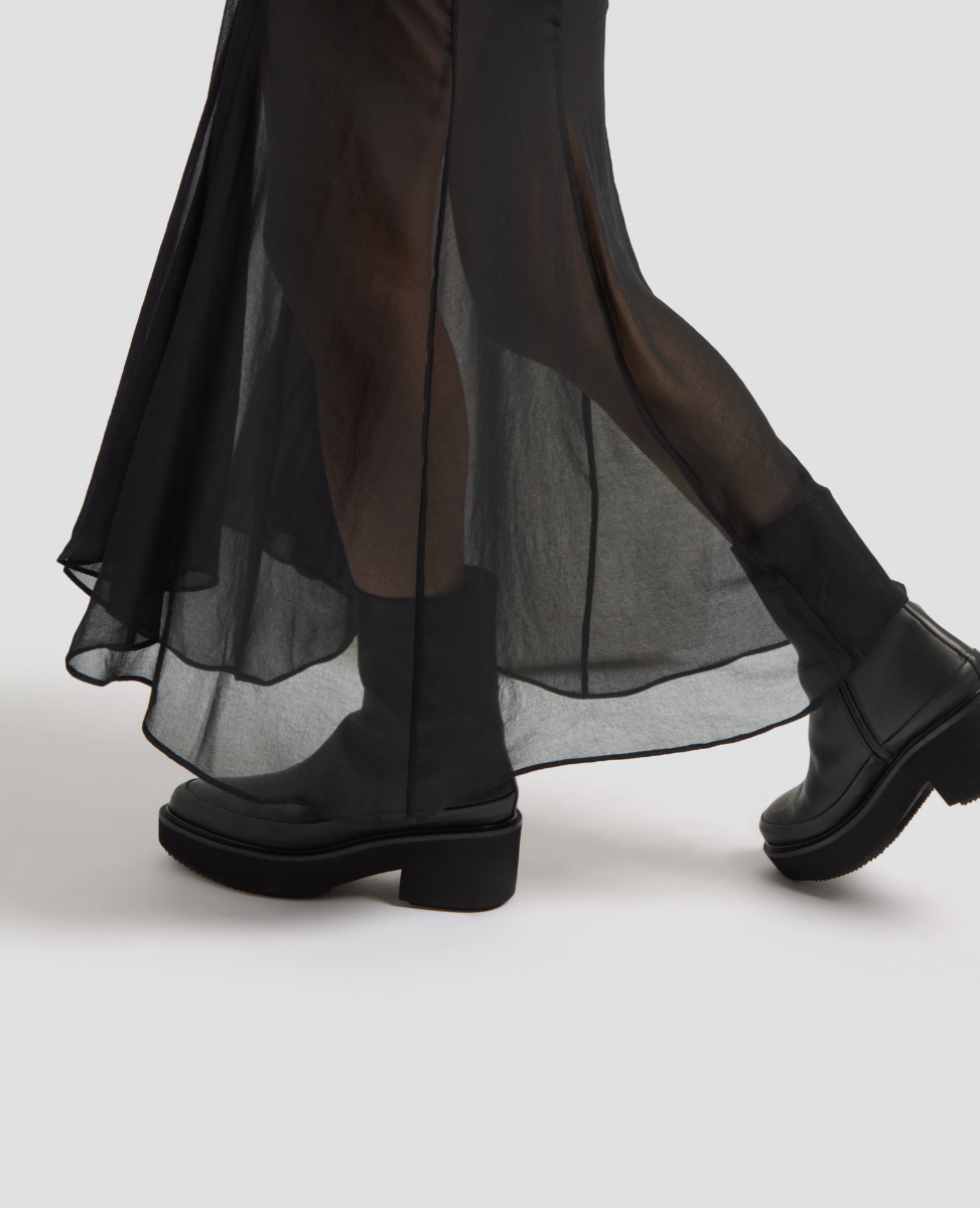 Black boots worn with a black dress on a white background