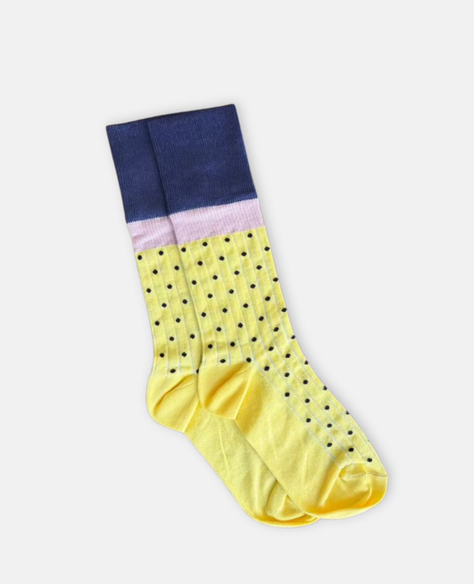 Yellow sock with black polka dots and a navy top section on a light gray background