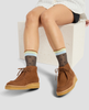 Person wearing brown suede shoes and patterned socks sitting on a white stool. 4