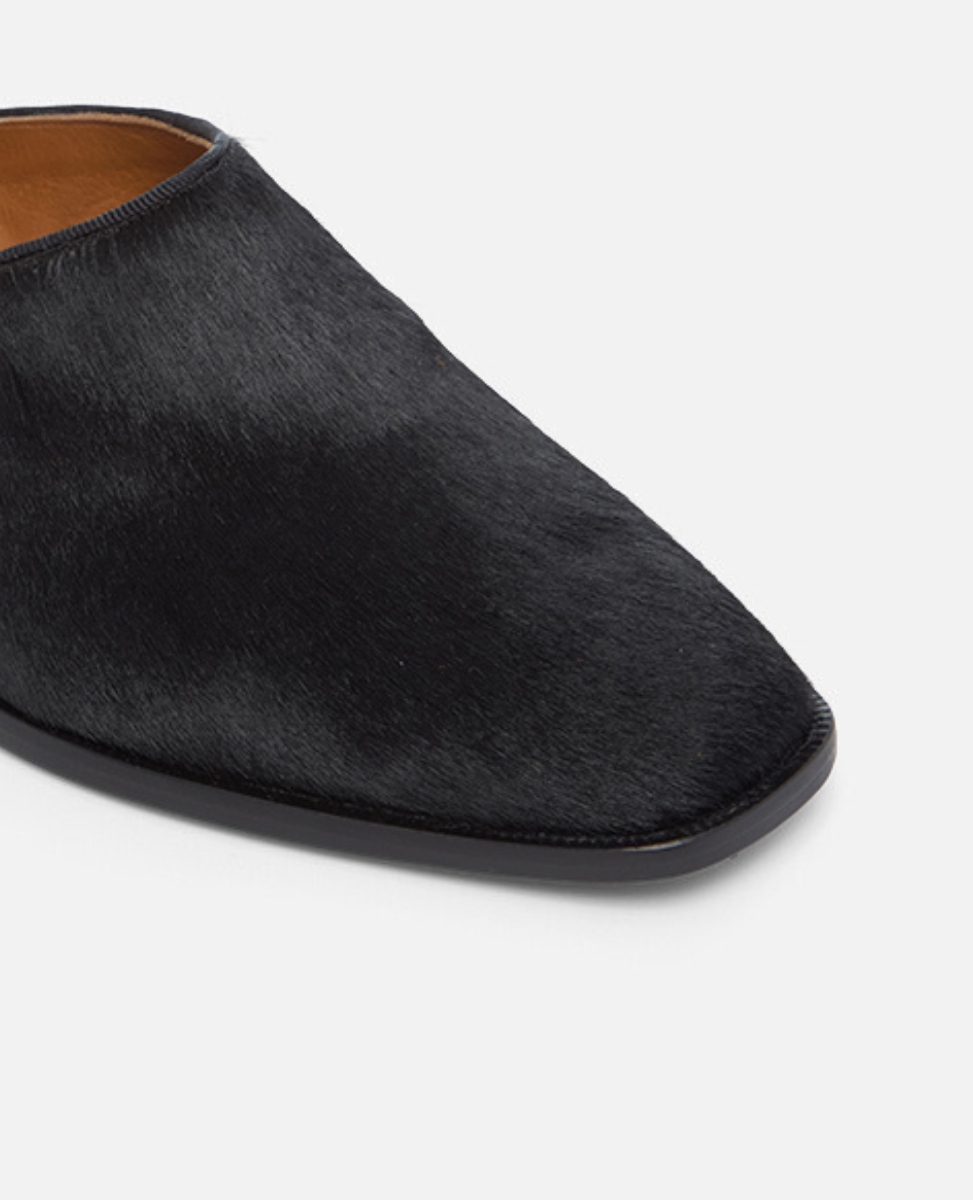 Black slip-on shoe on a light gray background