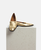 Gold loafers on a light gray pedestal against a white background 4