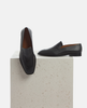 Black loafers on a light gray surface with a white background 4